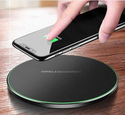 Wireless charger pad charging smartphone on wooden surface.