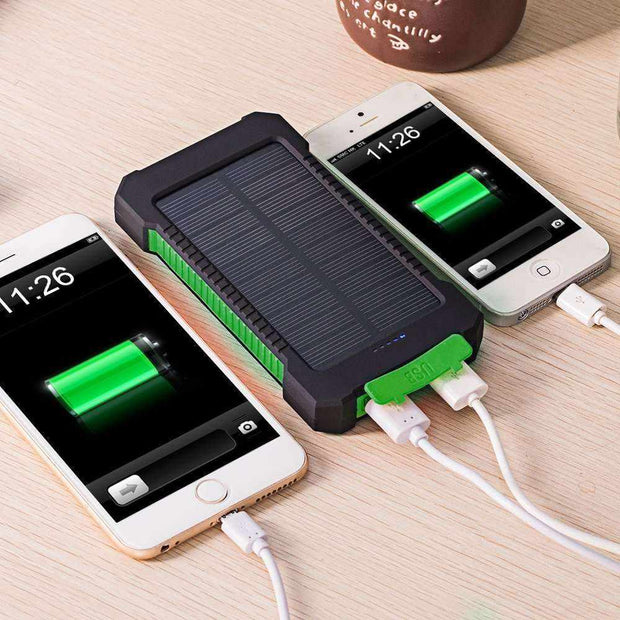 Solar Charger powering two smartphones with full battery indicators on a wooden desk.