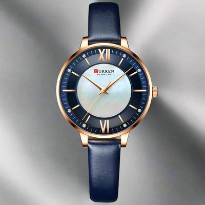 Ladies fashion watch with dark blue leather strap, quartz movement, and rose gold case with a round dial.