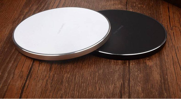 Wireless charging pads in black and silver on wooden surface.