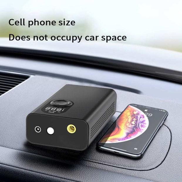 Portable vehicle-mounted multifunctional tire pump on car dashboard, compact size next to smartphone.