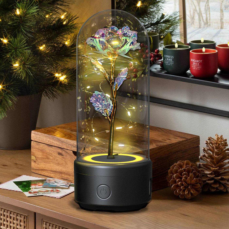 Rose flowers LED light and Bluetooth speaker in glass cover on a holiday-themed table.