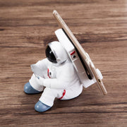 Cute astronaut phone stand holding a device, made of durable resin material.