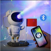 Astronaut-themed galaxy projector nightlight with Bluetooth, displaying starry sky effects, controlled by smartphone.