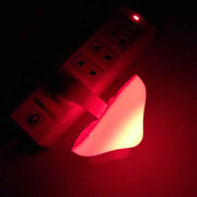 Mushroom-shaped LED night light plugged into wall socket, emitting a red glow.