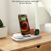 Folding magnetic wireless charger on nightstand charging phone, watch, and earbuds.