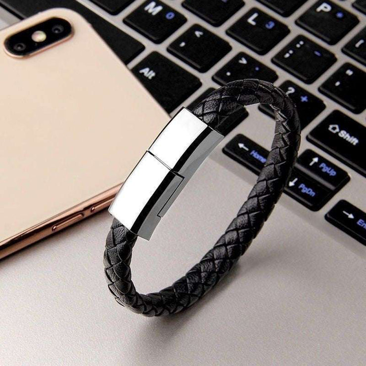 Black leather bracelet USB charger on a laptop keyboard.