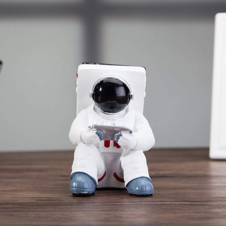 Cute astronaut phone stand on desk, creative resin holder for students.