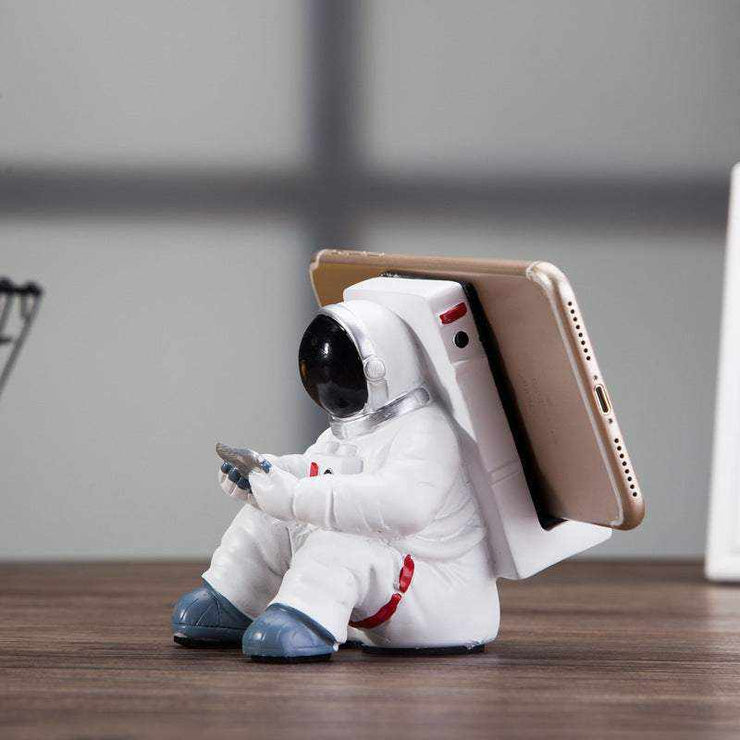 Cute astronaut phone stand made of resin, creative desktop holder for students and small desk decoration.