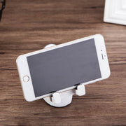 Cute astronaut phone stand holding a smartphone on a wooden desk.