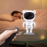 Astronaut-shaped galaxy projector nightlight on table with remote control.