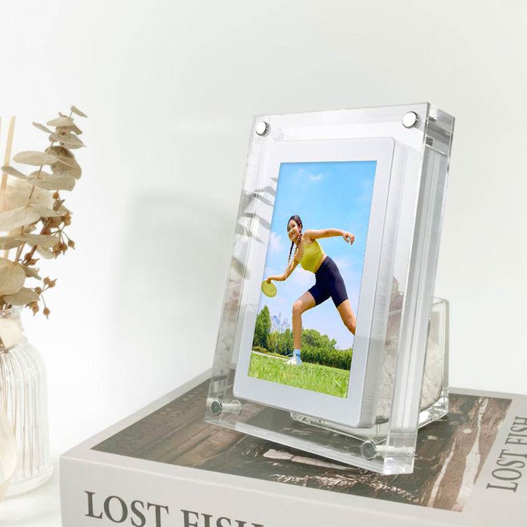 Acrylic digital picture frame on a book displaying a photo with a clear modern design.